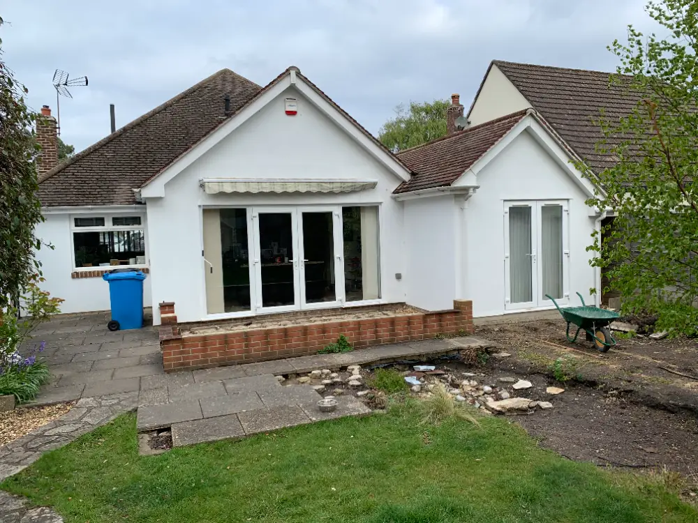 Rear of a 1960s Bournemouth bungalow before remodelling, with an awning, sliding patio doors and a raised brick step
