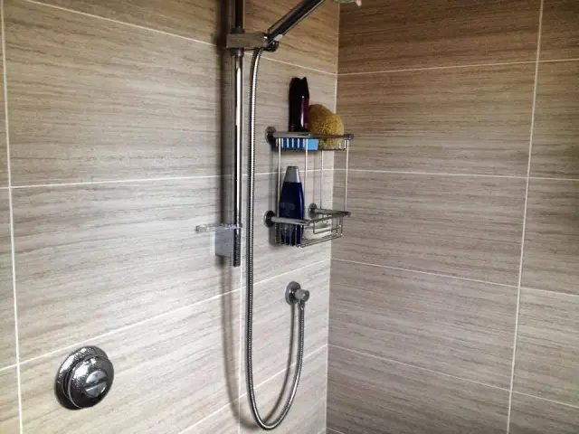 Wall-mounted shower fitting with storage basket