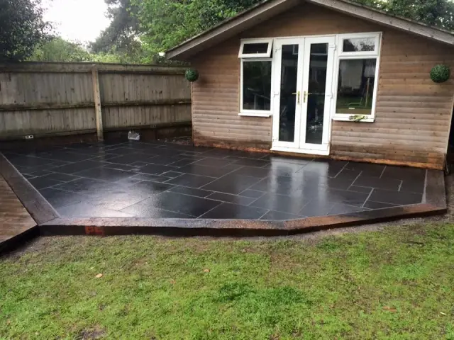 Dark slate patio installed beside garden room