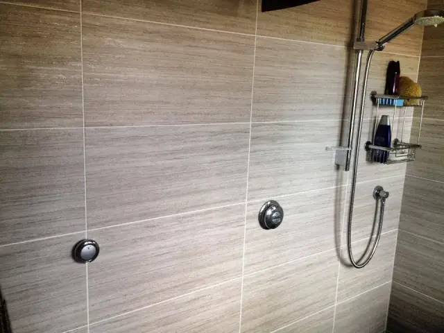 Tiled shower wall with chrome mixer controls