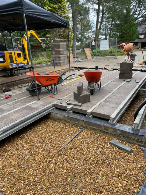 A beam and block floor going down, with wheelbarrows and a mini digger on site