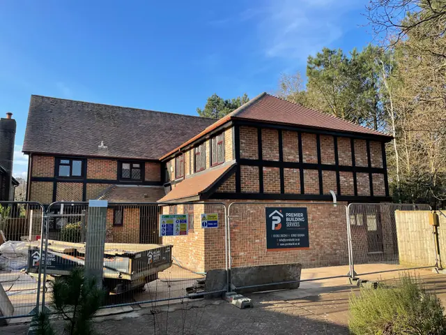 The front of the house with the new two storey extension, behind site fencing