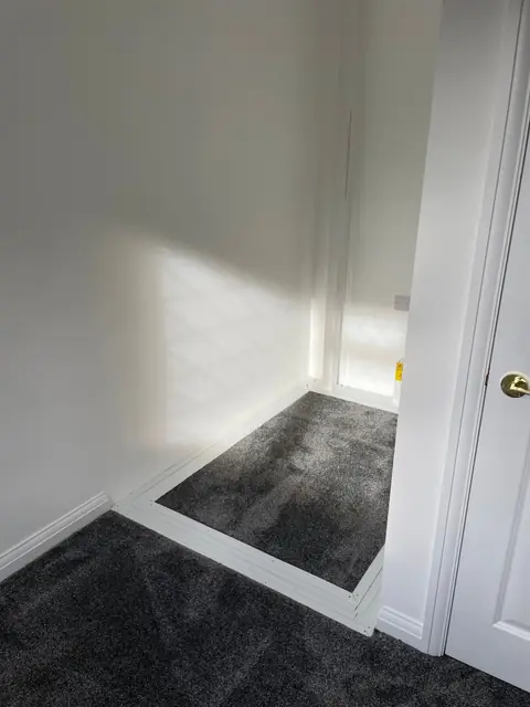 A newly finished room with grey carpet and white walls
