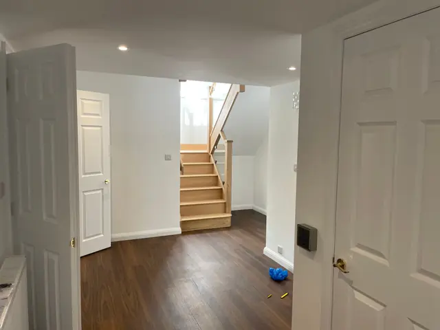 A hallway with wide doorways and the oak staircase