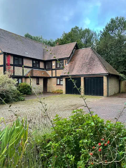 The front of the house before work started: a mock Tudor detached house with a double garage and a block paved drive