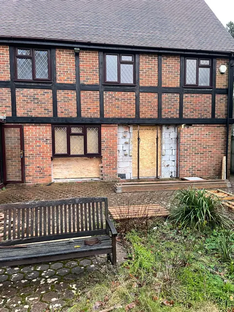 The rear of the house before the new openings were made, with boarded up windows and a garden bench