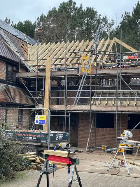 The extension roof frame and scaffolding, with a mitre saw set up on the drive
