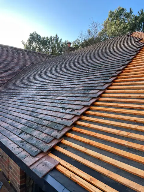 Plain clay roof tiles being laid over the battens