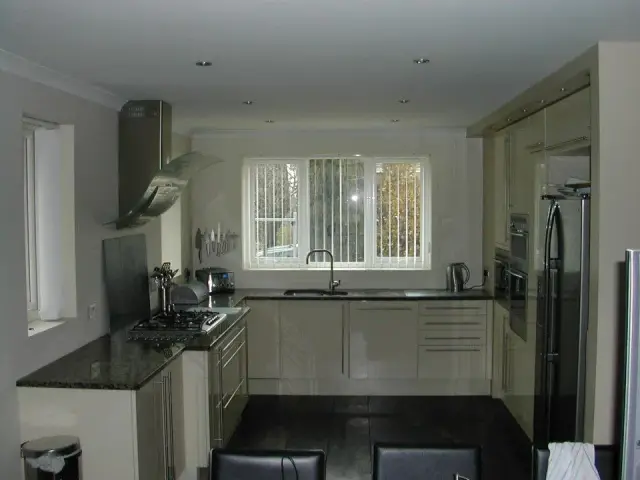 Cream gloss fitted kitchen with dark tiled floor