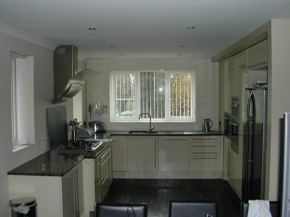 Cream gloss fitted kitchen with dark tiled floor