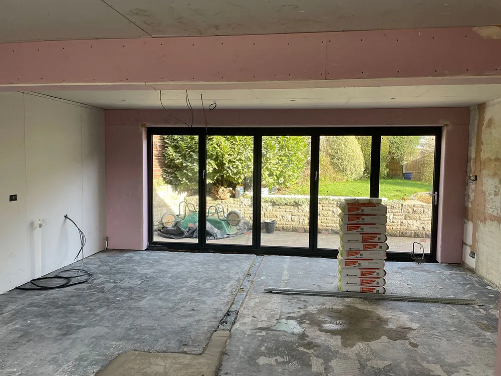 Kitchen before renovation: a bare extension shell with a concrete floor, unfinished walls and new bi-fold doors