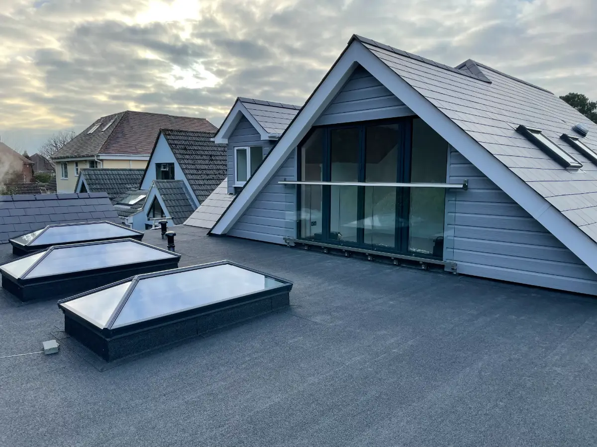 Finished loft conversion with a roof terrace, glass roof lanterns and a glass balustrade