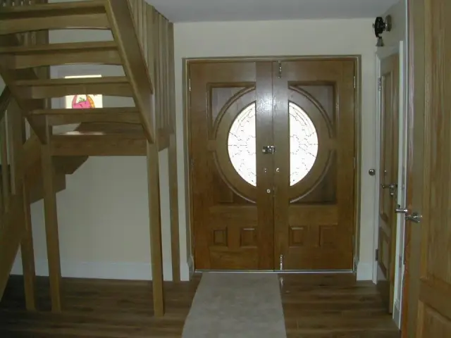 Hallway with oak staircase and round window door
