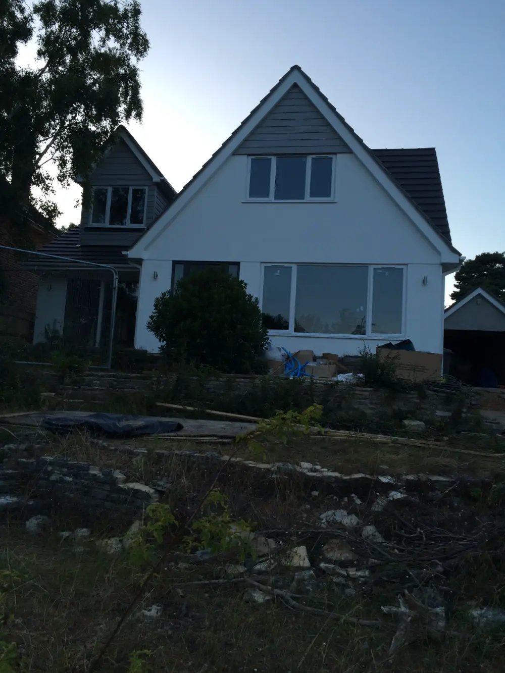 Newly rendered chalet bungalow with grey cladding and new windows