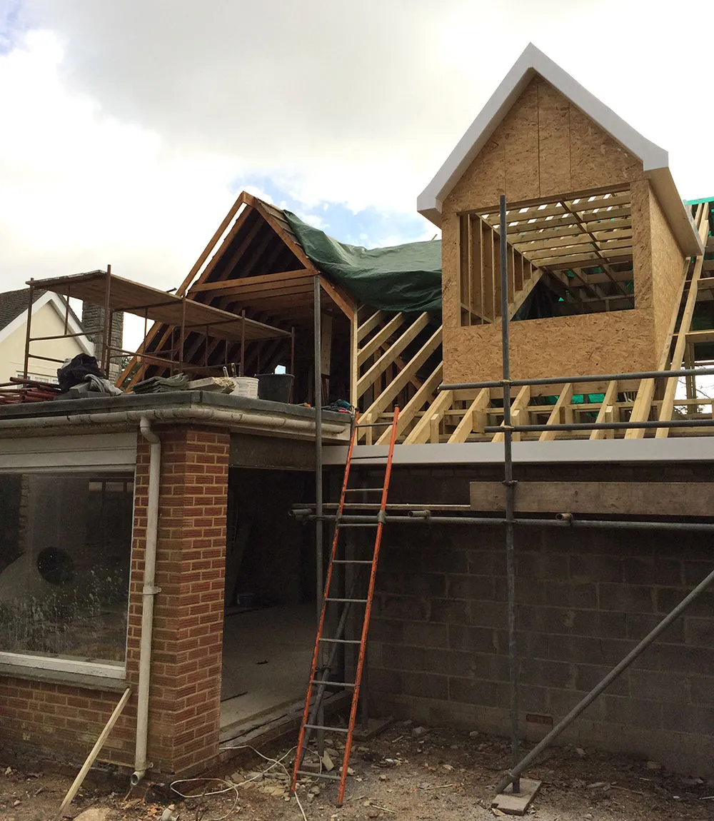 Rear extension under construction, with new blockwork walls, a timber roof frame and a gable dormer sheathed in OSB boarding