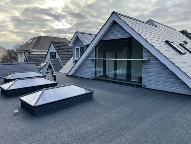 Two pitched roof lanterns on the extension’s flat roof, with the new glazed gable and grey clad dormers behind